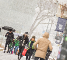 People dressed for cold weather walking in the snow at UBC.